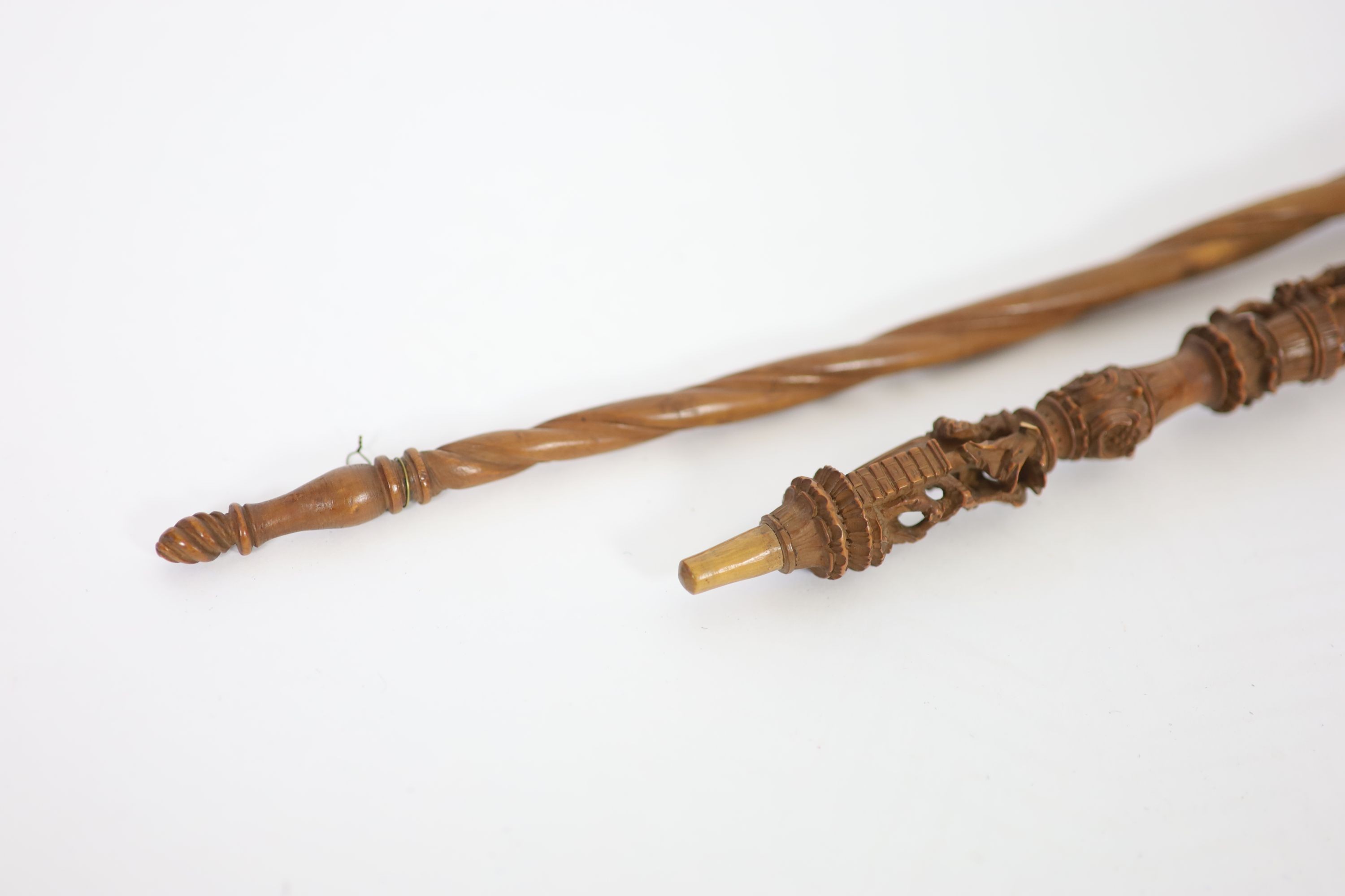 A 17th century French boxwood distaff (wool winder), carved with numerous figures and scrolls, over a spiral fluted stem, 49 & 36cm.